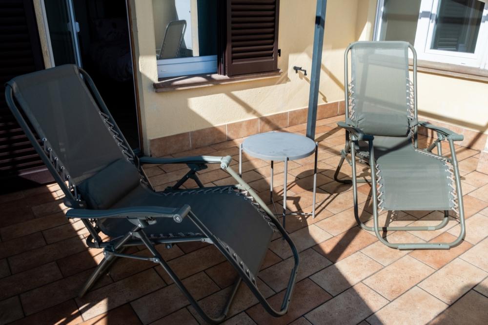 Terrazzo esterno soleggiato della Camera Papavero al B&amp;B C'era una volta, arredato con due sedia a sdraio reclinabili e un tavolino rotondo.