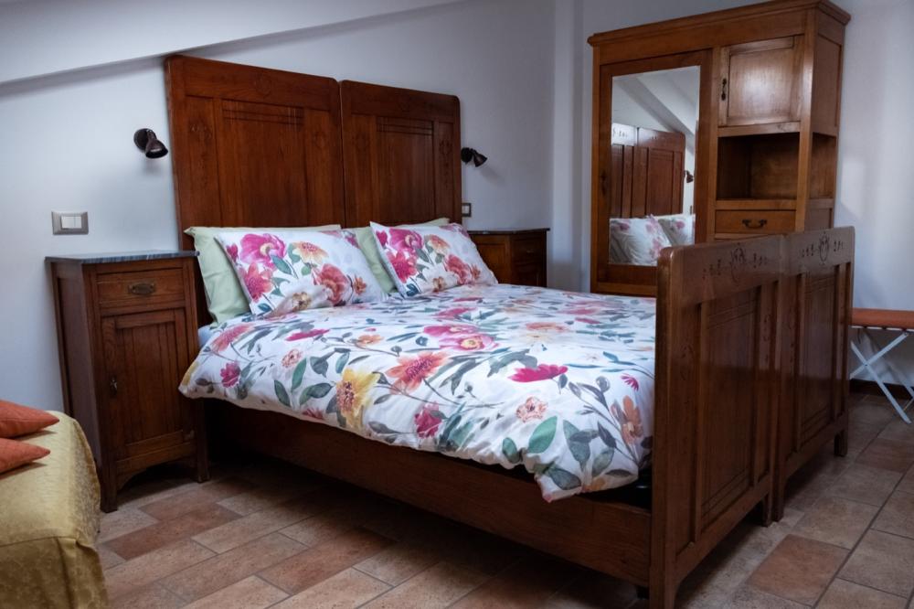 Letto matrimoniale e armadio in legno antico restaurato con specchio nella Camera Girasole del B&B C'era una volta.