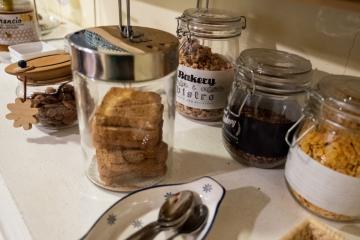 Buffet della colazione continentale al B&amp;B C'era una volta con succhi di frutta, brioche, dolci sotto campane protettive e una stampa di Banksy a parete.