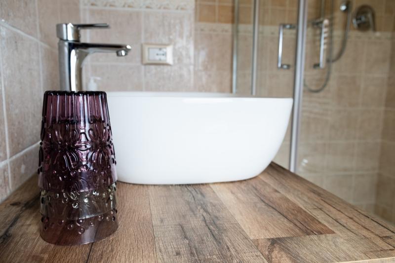 Il moderno bagno della Camera Papavero presso il B&B C'era una Volta, con lavabo d'appoggio e top in legno.