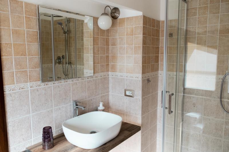 Il moderno bagno della Camera Papavero presso il B&B C'era una Volta, con lavabo d'appoggio e top in legno.