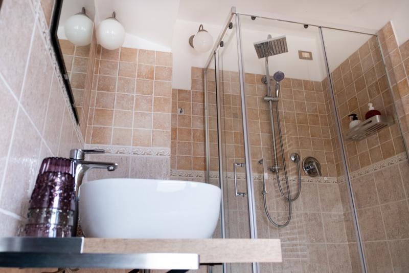 The modern bathroom of the Papavero Room at C'era una Volta B&B, featuring a stylish vessel sink and wooden counter