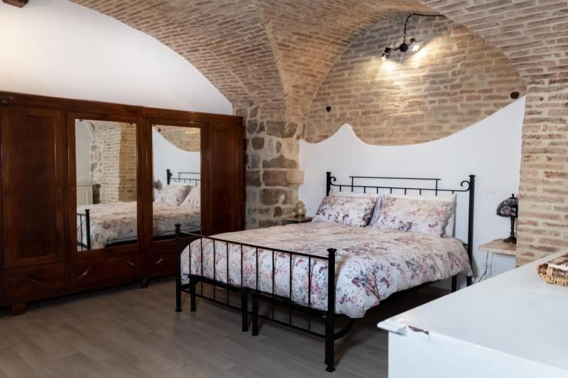 Una suggestiva camera da letto storica, dove le antiche volte in mattoni e i mobili antichi creano un'atmosfera romantica e senza tempo.