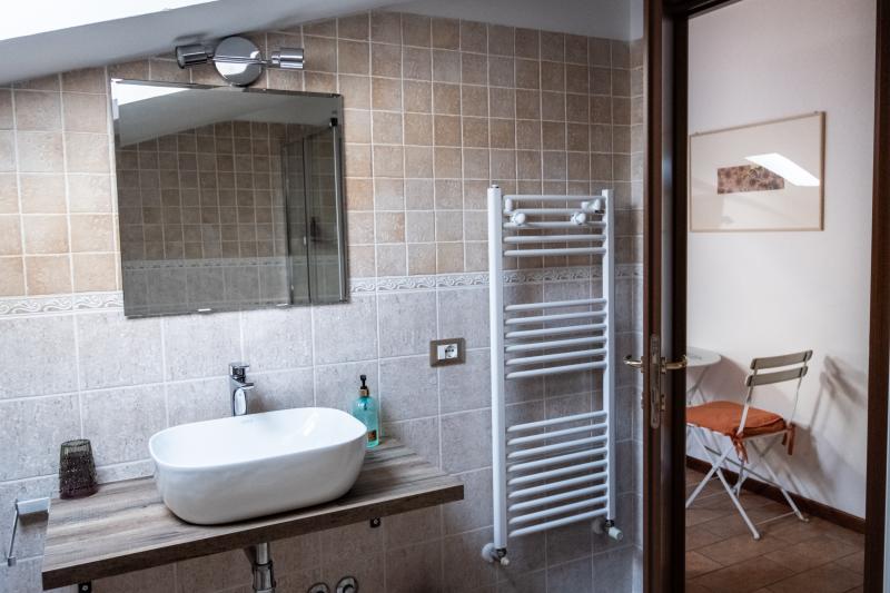 Bright attic private bathroom with modern fixtures and a wooden washbasin console.