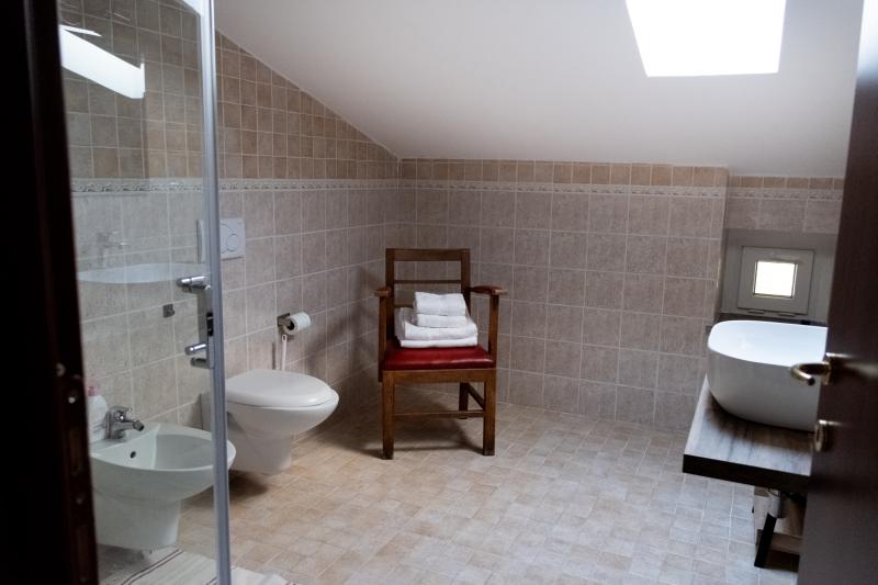 Bright attic private bathroom with modern fixtures and a wooden washbasin console.