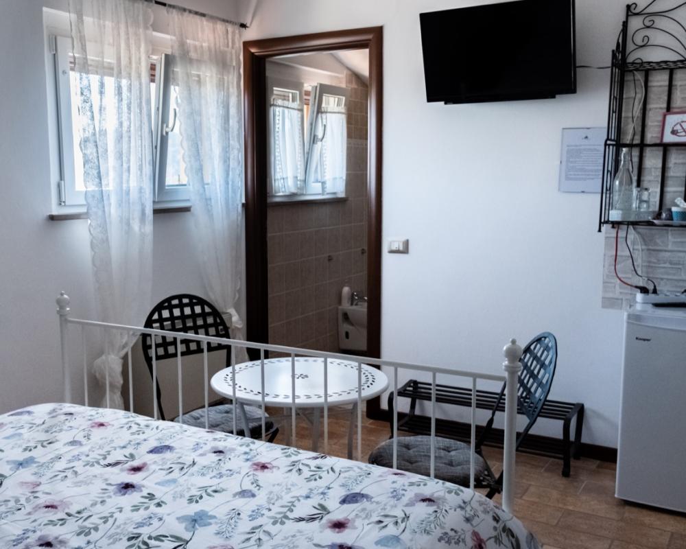 Camera matrimoniale Peonia del B&amp;B C'era una volta con letto in ferro battuto bianco e una finestra luminosa che offre una splendida vista sulle antiche mura di Perugia.