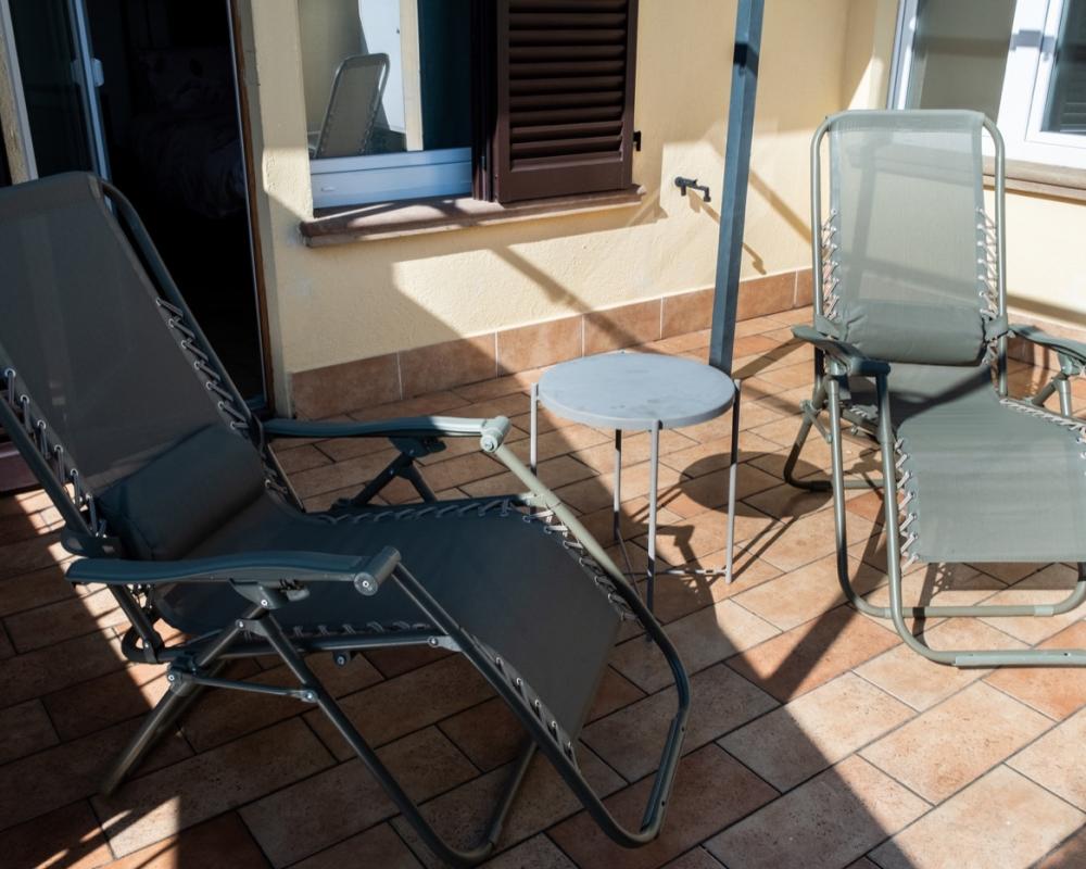 Terrazzo esterno soleggiato della Camera Papavero al B&amp;B C'era una volta, arredato con due sedia a sdraio reclinabili e un tavolino rotondo.