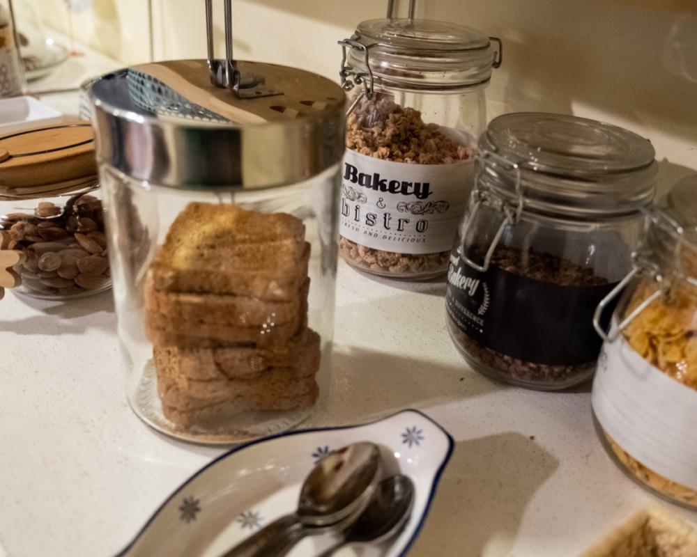 Buffet della colazione continentale al B&amp;B C'era una volta con succhi di frutta, brioche, dolci sotto campane protettive e una stampa di Banksy a parete.