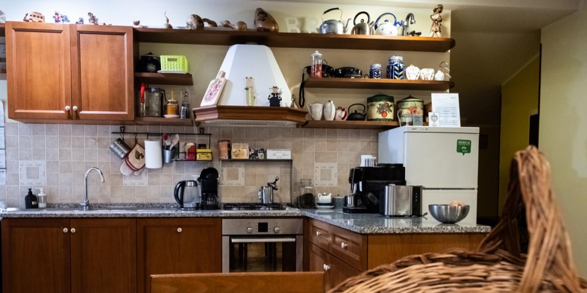 Cucina tradizionale e sala colazione del B&amp;B C'era una volta, con un grande tavolo in legno intarsiato, mobili classici in legno, bollitore e pavimento in cotto.