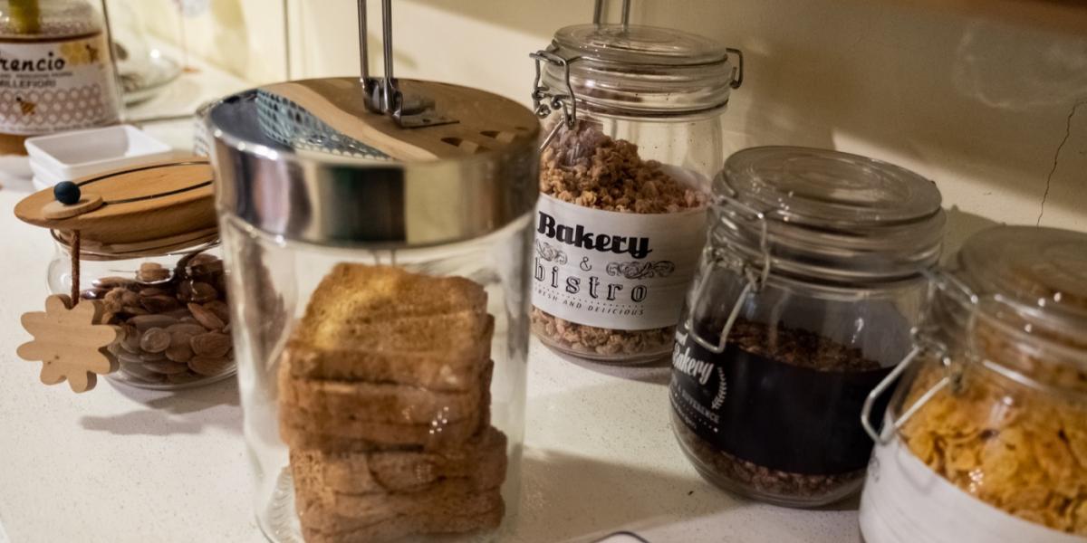 Buffet della colazione continentale al B&amp;B C'era una volta con succhi di frutta, brioche, dolci sotto campane protettive e una stampa di Banksy a parete.